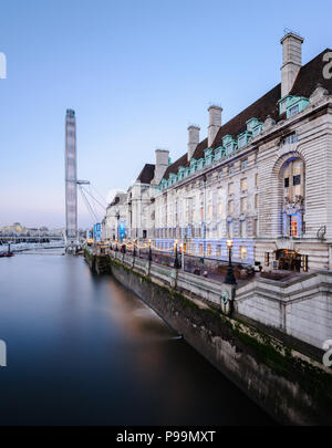 Lange Belichtung Hochformat der Coca-Cola-London Eye und der County Hall von Westminster Bridge, London, in der Dämmerung, mit einem klaren blauen Himmel Stockfoto