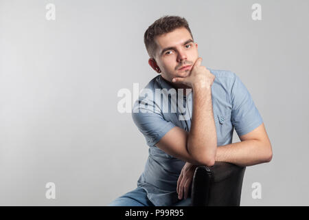 Stattliche ernster Mann sitzen und denken. Schauspieler portfolio Bild, Emotionen und Gefühle. Studio shot, auf grauem Hintergrund Stockfoto