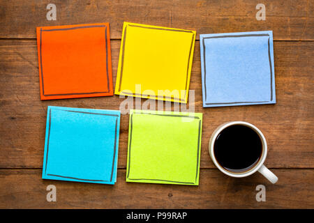 Set aus bunten, leere Erinnerung Notizen auf einem grunge Holztisch mit einer Tasse Espresso Stockfoto