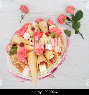 Original Blumenstrauß aus Blüten von Rosen, Waffeln, Süßigkeiten und Marshmallows auf einem hellen Hintergrund Stockfoto