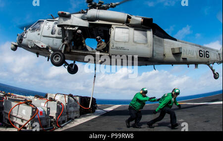 180716-N-OY 799-0410 philippinischen Meer (Juli 16, 2018) Fachkraft für Lagerlogistik 3. Klasse Jakob Chesney, von Allen, Texas, Recht und Logistik Specialist Seaman Kendrick Baquero, aus New York, dass sich im Bereich als MH-60S Sea Hawk, Hubschrauber Meer Combat Squadron (HSC) 12, bereitet die Fracht vom Flight Deck der Marine voranzubringen zugeordnet - bereitgestellt Flugzeugträger USS Ronald Reagan (CVN 76) während einer Auffüllung-auf-See mit Military Sealift Command flotte Auffüllung öler USNS Walter S. Diehl (T-AO 193). Ronald Reagan, das Flaggschiff der Carrier Strike Group 5, bietet eine combat ready fo Stockfoto