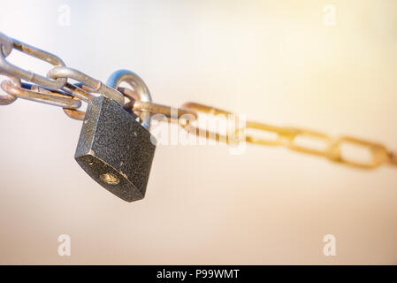 Metallschloss mit Kette auf unscharfen sonnigen Hintergrund Stockfoto