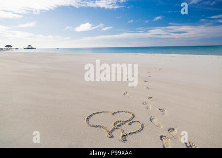 Zwei Herzen im weißen Sand am tropischen Strand Szene gezeichnet Stockfoto