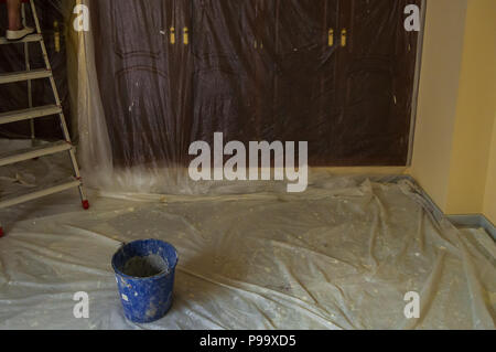Malerei das Schlafzimmer des Hauses. Zimmer mit Möbel und Schränke geschützt mit Kunststoff zu malen. Eine Reform zu Hause. Stockfoto