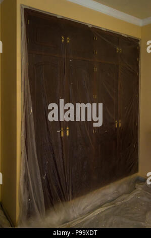 Malerei das Schlafzimmer des Hauses. Zimmer mit Möbel und Schränke geschützt mit Kunststoff zu malen. Eine Reform zu Hause. Stockfoto