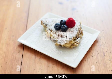 Mit Puderzucker und Beeren auf einem Schild an einem Holztisch Kaiserschmarren Stockfoto