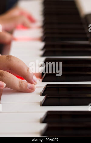 Hand auf einer Klaviertastatur mit roten Lichter in die Tasten Stockfoto