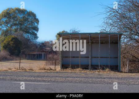 Eine leere gewellte (verzinkte) eiserne Bushaltestelle neben der Straße in Wattle Flat im ländlichen New South Wales, Australien Stockfoto