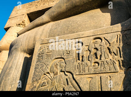 Nahaufnahme Detail aus Granit gehauen Hieroglyphen an der Basis der Kolosse sitzende Figur von Ramses II., den Tempel von Luxor, Luxor, Ägypten, Afrika Stockfoto