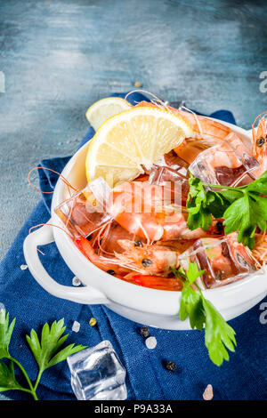 Meeresfrüchte, Gekochte Garnelen mit Zitrone und Eis auf einem hellblauen Hintergrund Stockfoto