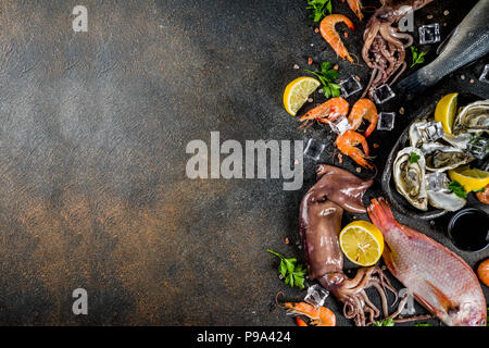 Frische rohe Meeresfrüchte squid Garnelen oyster Miesmuscheln Fisch mit Gewürzen der Kräuter Zitrone auf dunklen rusty Background Copy space Top View Stockfoto