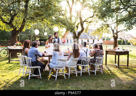 Braut und Bräutigam mit Gästen in Hochzeit außerhalb im Hinterhof. Stockfoto