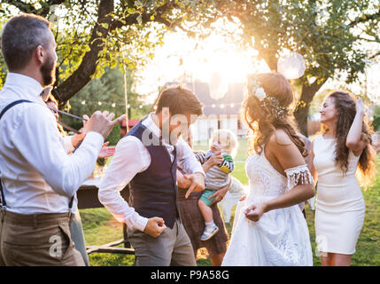 Braut und Bräutigam tanzen an der Hochzeit außerhalb im Hinterhof. Stockfoto