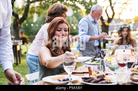Gäste essen auf der Hochzeitsfeier draußen im Hinterhof. Stockfoto