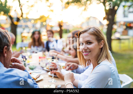 Braut und Bräutigam mit Gästen in Hochzeit außerhalb im Hinterhof. Stockfoto