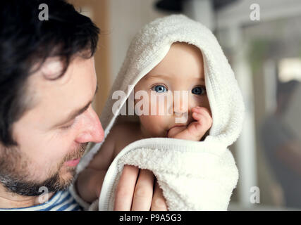 Vater mit einem Kleinkind Kind im Handtuch im Bad zu Hause eingepackt. Stockfoto