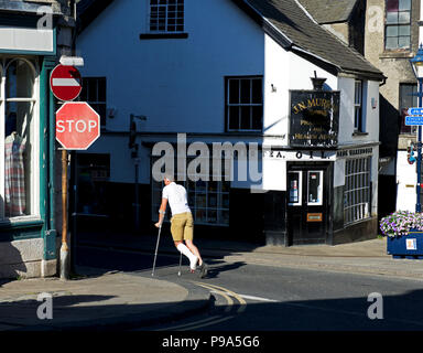 Junger Mann auf cutches, mit Fuß in Gips, Ulverston, Cumbria, England Großbritannien Stockfoto