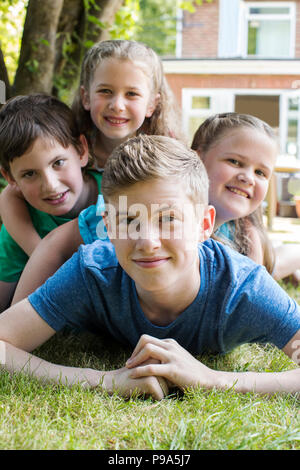 Porträt der vier Brüder und Schwestern Liegen im Garten zu Hause Stockfoto