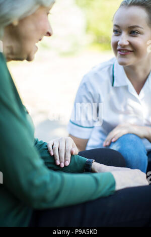 Ältere Frau im Garten im Gespräch mit weiblichen Pflegeperson Stockfoto