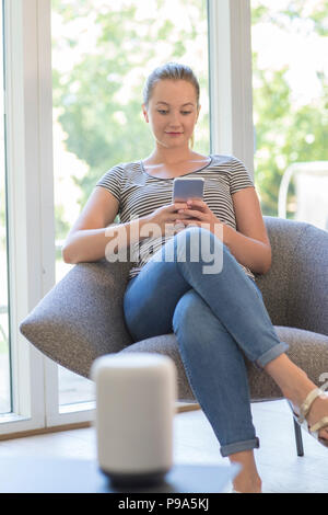Frau streamt Musik vom Handy, kabellose Lautsprecher Stockfoto