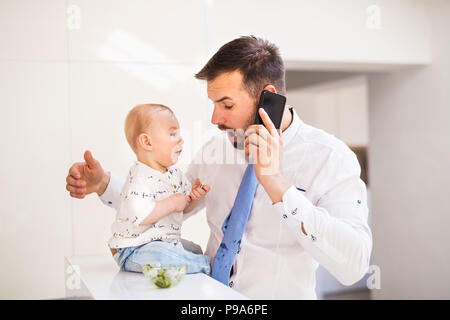 Ein baby boy, seine Väter Riegel schmutzig, wenn Essen. Stockfoto