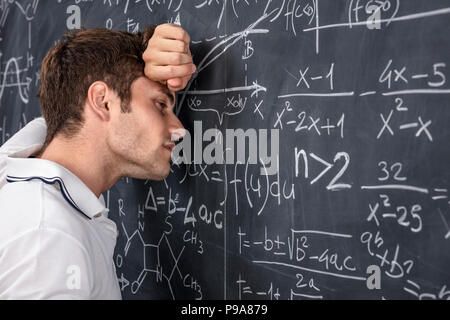 Betonte student lehnt sich an klassischen schwarzen Brett Stockfoto