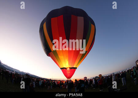 Farbenfroher Heißluftballon, bereit für den Start bei Sonnenaufgang, Silhouette vor dem Dämmerungshimmel beim Albuquerque International Balloon Fiesta, New Mexico, USA Stockfoto