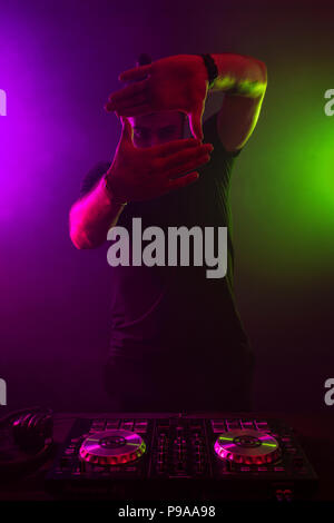 Attraktive junge DJ spielen auf Plattenspieler mit Farbe Licht Effekte Stockfoto