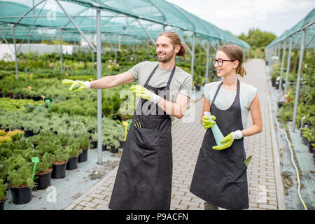 Junge paar Arbeiter in Uniform Betreuung von Pflanzen im Gewächshaus Stockfoto