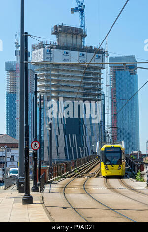 Die Achse und Deansgate Square Apartment Blocks (im Bau) mit einem Metrolink Tram im Vordergrund, von der unteren Mosley Street, Manchester, UK Stockfoto