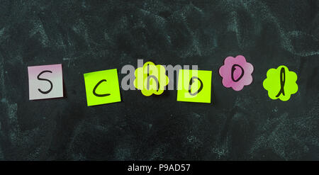 Schule Konzept. Bunte Haftnotizen, mit Buchstaben schreiben Schule, in verschiedenen Formen und leeren Raum, auf blackboard Hintergrund isoliert. Stockfoto