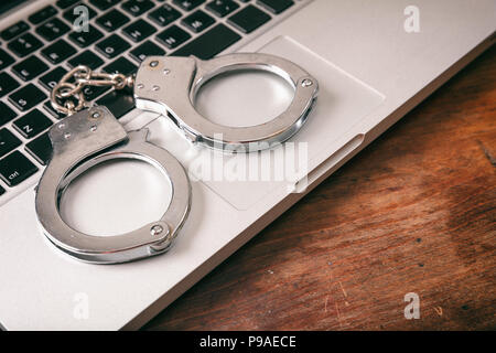 Cyberkriminalität Konzept. Handschellen auf einem Computer auf einer hölzernen Hintergrund, kopieren. Stockfoto