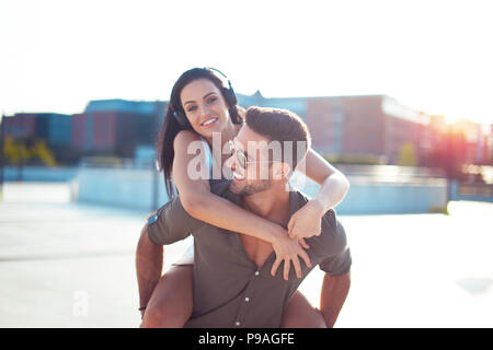 Glückliche junge trendige Urban Paar viel Spaß in Stadt, Huckepack Reiten Stockfoto