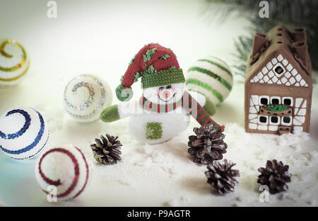 Spielzeug Schneemann und ein Lebkuchenhaus auf einem hellen Hintergrund. Stockfoto