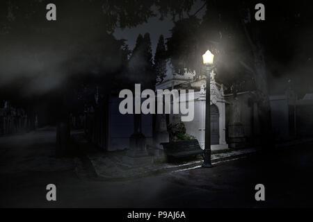 Alte europäische Friedhof durch eine Straßenlaterne in einer nebligen Nacht beleuchtet Stockfoto