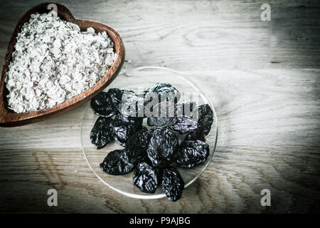 Pflaumen in einer Schale und Getreide auf einem Holztisch Stockfoto