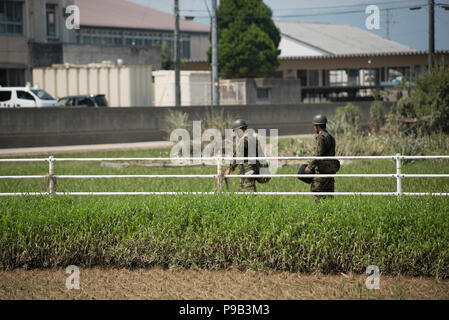 Okayama, Japan. 17. Juli 2018. Soldaten gehen unter Beschädigte Reisfelder bei Flut Reinigung in Mabicho, Kurashiki, Okayama Präfektur, Japan. Mehr als 200 Tote bei Überschwemmungen und Erdrutschen durch sintflutartige Regenfälle vor mehr als einer Woche verursacht. Am Sonntag kündigte die Regierung das Wetter bei einem extrem schweren Katastrophe bezeichnet werden würde, wodurch Mittel für die Wiederherstellung der betroffenen Gebiete. Aufräumarbeiten und Wiederaufnahme Bemühungen wurden durch extreme Hitze behindert wurde. Quelle: Lba Co.Ltd./Alamy leben Nachrichten Stockfoto