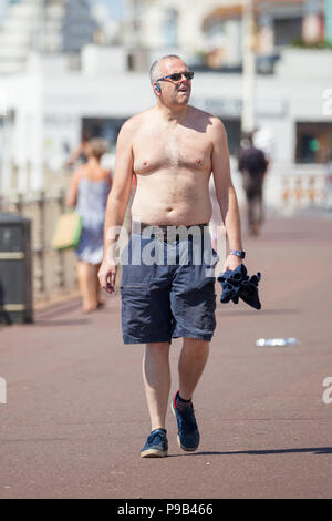 Hastings, East Sussex, UK. 17 Jul, 2018. UK Wetter: Heiß und sonnig Wetter in Hastings, East Sussex mit intermittierender Wolken aber eine willkommene Brise in der Luft. Viele Menschen genießen die anhaltende Hitzewelle noch Großbritannien schlägt. Temperaturen um 25°C überschreitet. Ein Mann Spaziergänge entlang der Strandpromenade mit seinem Hemd aus Musik zu hören. Foto: Paul Lawrenson/Alamy leben Nachrichten Stockfoto