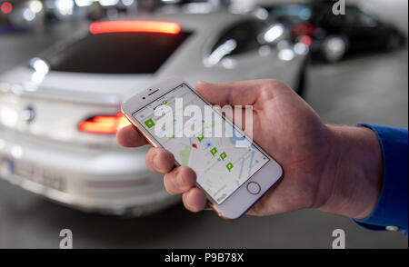 Hamburg, Deutschland. 16. Juli 2018. Ein Mann hält ein Smartphone in seinen Händen, die die Apcoa app am Auto Parkplatz am Gänsemarkt (lit. gänse Markt). Apcoa führt ein Client App die Suche nach einem Parkplatz mehr einfach zu machen. Auf der Car Parks mit mehr als 100.000 Parkplätze in ganz Deutschland, Kunden sollen in der Lage sein, zu betreten und zu verlassen, ohne ein Ticket und automatisch und ohne Bargeld. Quelle: Axel Heimken/dpa/Alamy leben Nachrichten Stockfoto