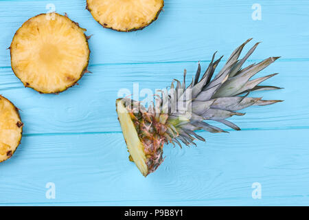 Frisch geschnittene Kreis Scheiben Ananas. Flach Ananas Krone auf Blau Holz- Oberfläche. Gesunde Essbare Pflanze. Stockfoto