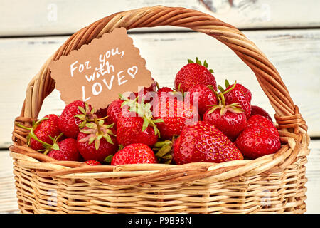 Korb voller Erdbeeren und Papier Karte. Frisch gepflückte Erdbeeren im Weidenkorb. Sommer gesunden Zutaten. Stockfoto