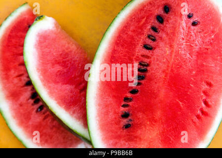 Scheiben der ganze frische Wassermelone von oben auf der gelben Tabelle. Stockfoto