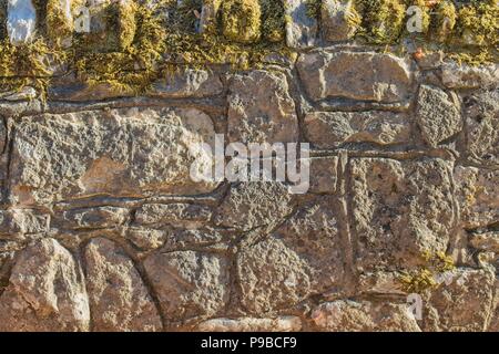 Sandsteinmauer mit Moos im Sonnenschein Stockfoto