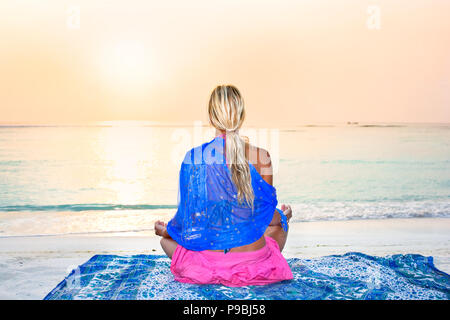 Junge Frau die Sonne genießen und Meditieren am tropischen Strand bei Sonnenaufgang Stockfoto