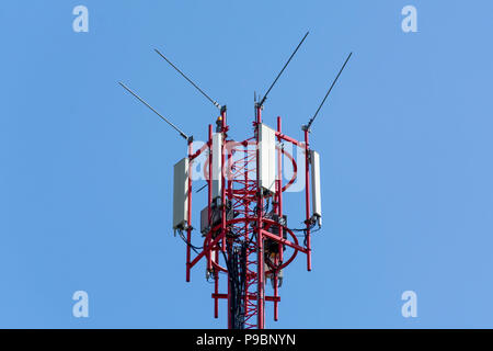 Nahaufnahme von Telekommunikationsturm mit roten Antennen mit blauen Himmel. Mobile phone Communication Equipment Konzept. Stockfoto