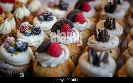 Cremige überstieg Cupcakes mit Plätzchen und Obst Stockfoto