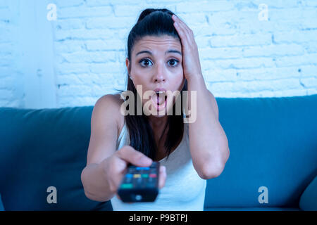 Junge schöne Latin Frau zu Hause Sofa sitzen im Wohnzimmer fernsehen scary Horror Film oder schreckliche Nachrichten ängstlich und aufgeregt, Abdeckung Stockfoto