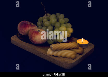 Noch immer leben aus der Dunkelheit. Komposition mit Obst, Kuchen und Kerzenschein. HD-Bildqualität. Stockfoto