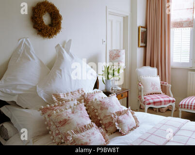 Twig Kranz über dem Bett mit weißen Kissen und Pink + weiß Toile de Jouy Kissen in der traditionellen weißen Schlafzimmer Stockfoto