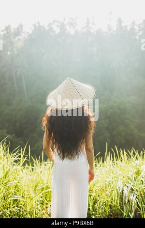 Portrait von jungen asiatischen Frau in traditioneller balinesischer Strohhut. Morgensonne in Ubud Reisfelder. Die chinesische Kultur Stockfoto